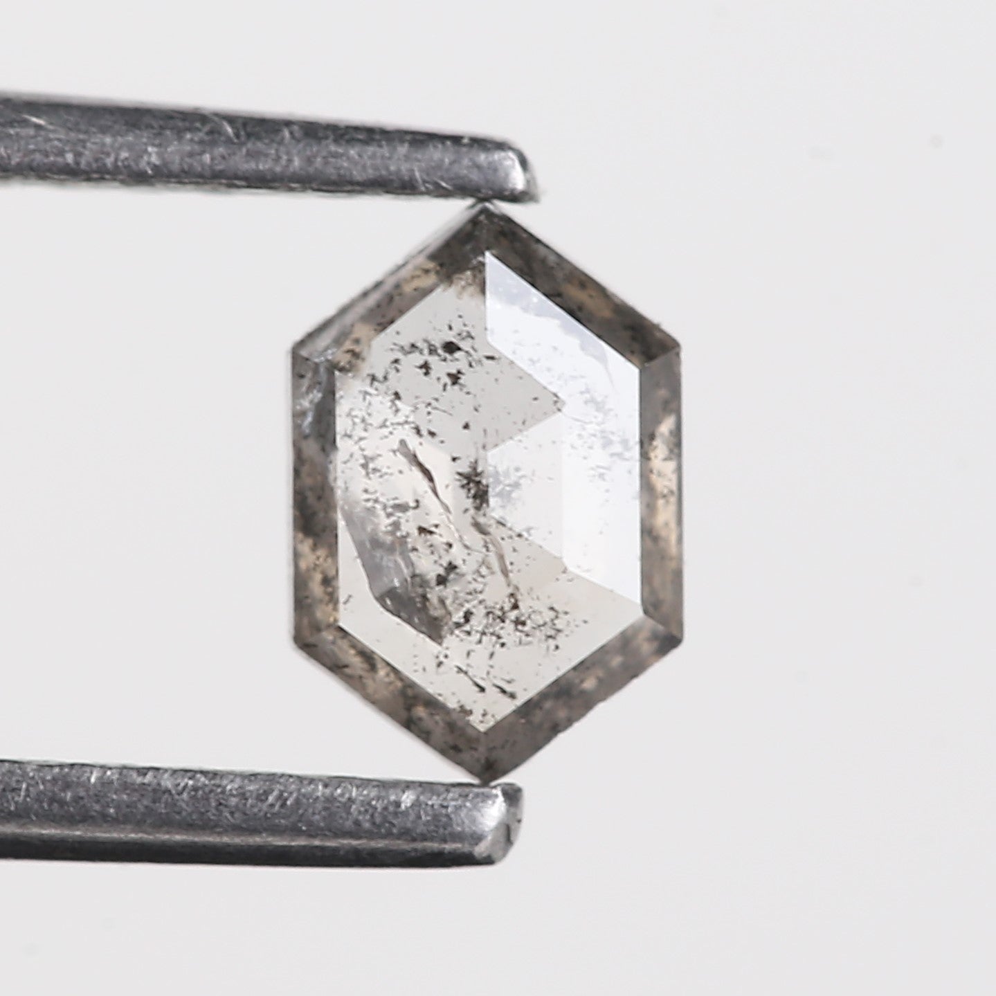 Hexagonal clear crystal with a metallic sheen on a light gray background