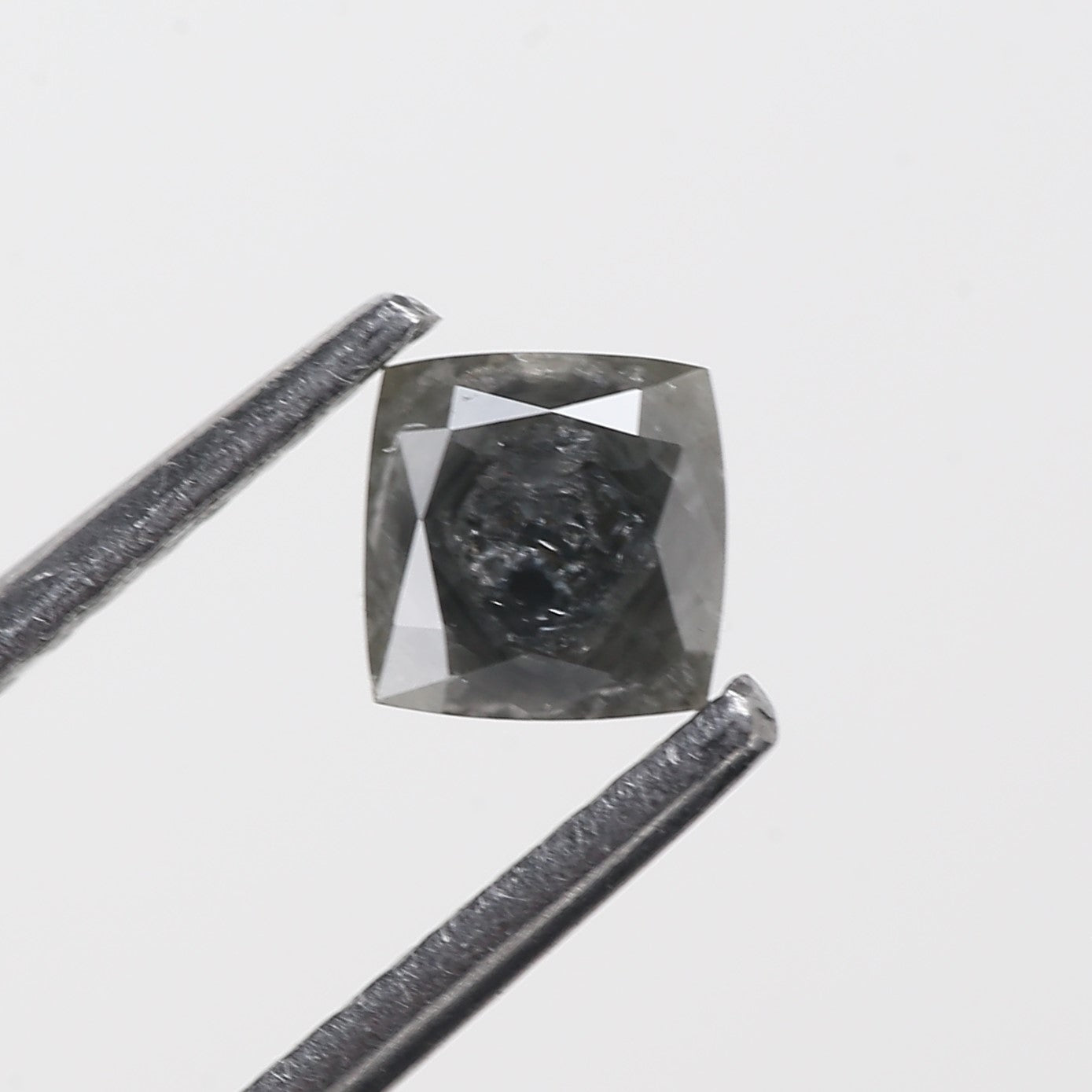 Gray diamond with a ruler for scale on a light gray background