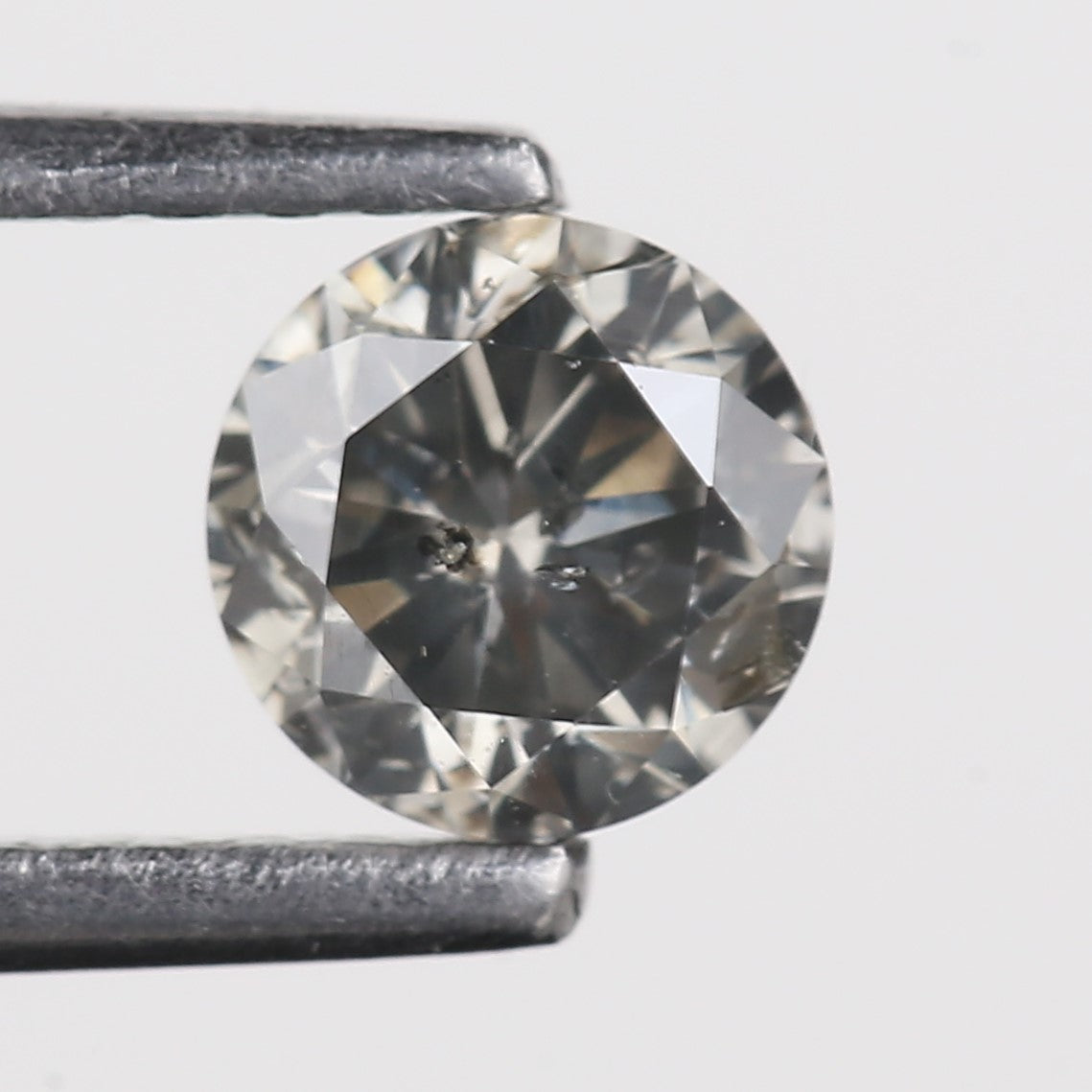 Round diamond held between two metal prongs on a light gray background