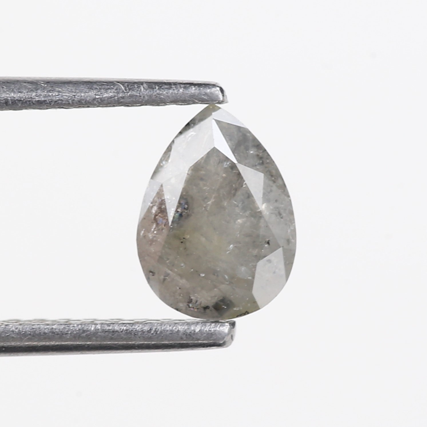Faceted gemstone held between two metal rods on a white background