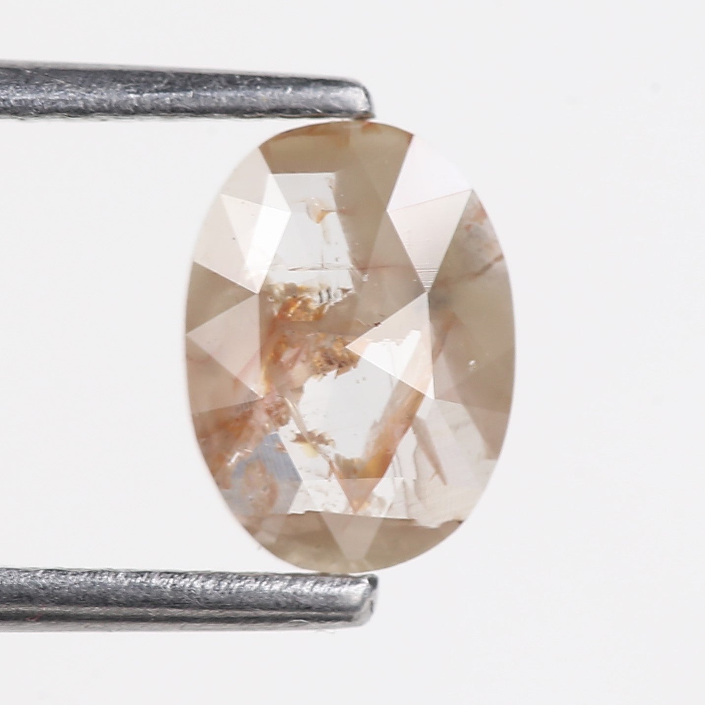 orange diamond held between two tweezers on a white background