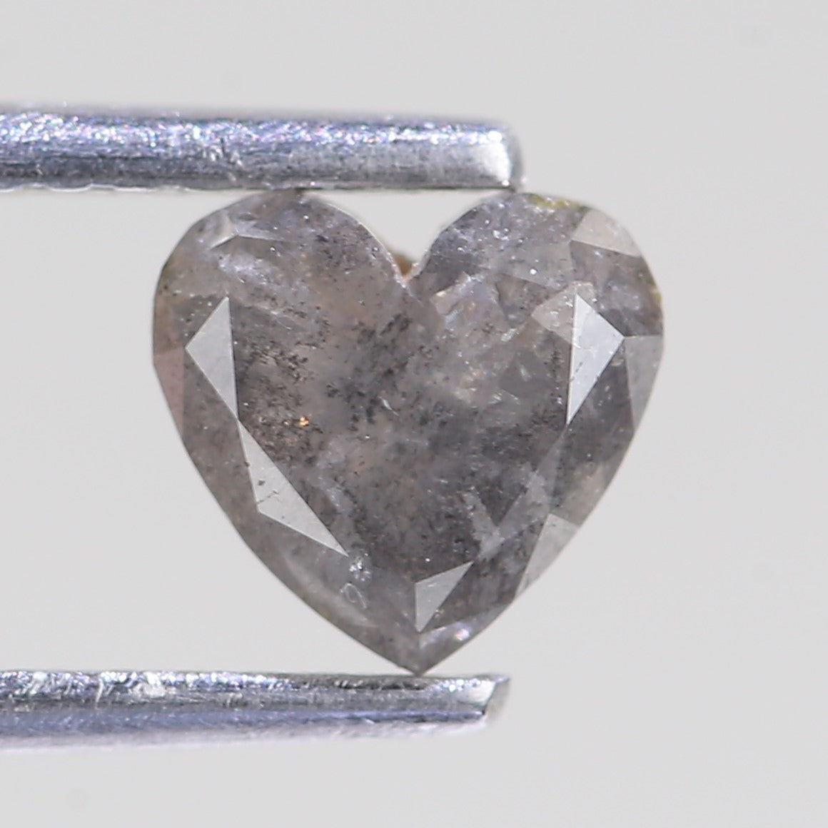 Heart-shaped diamond on a white background with a silver bar for scale.