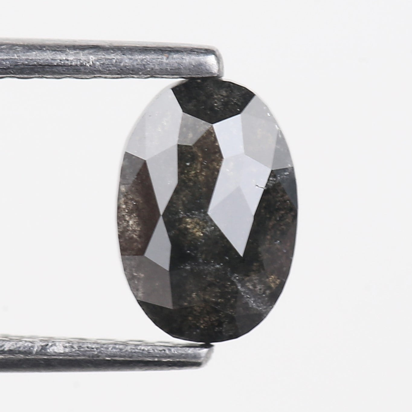 Faceted oval held between two metal prongs on a white background