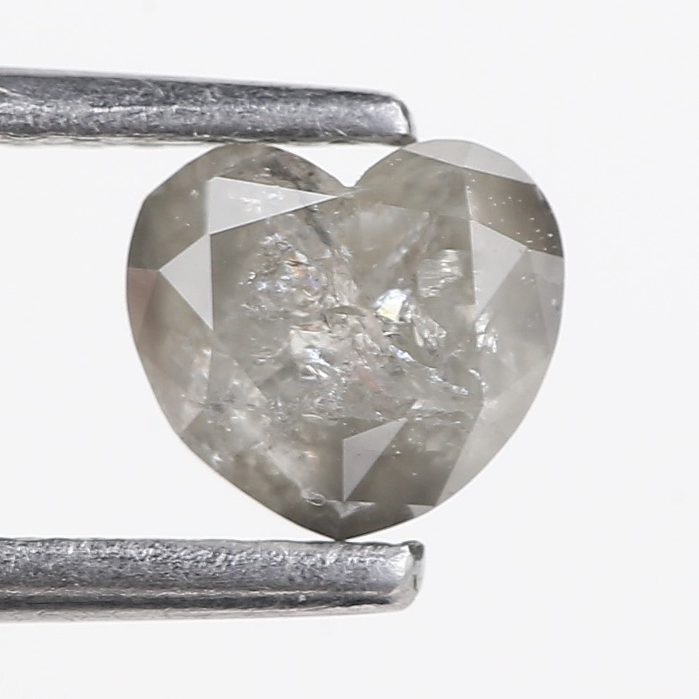 Heart-shaped diamond between two metal prongs on a white background