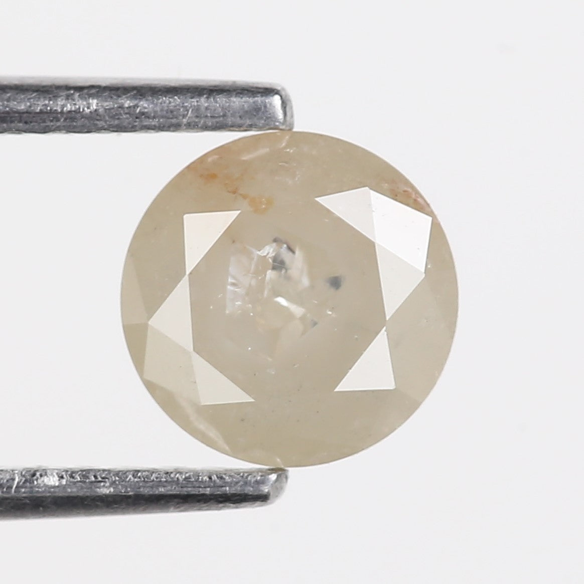 Faceted diamond held between two metal bars on a white background