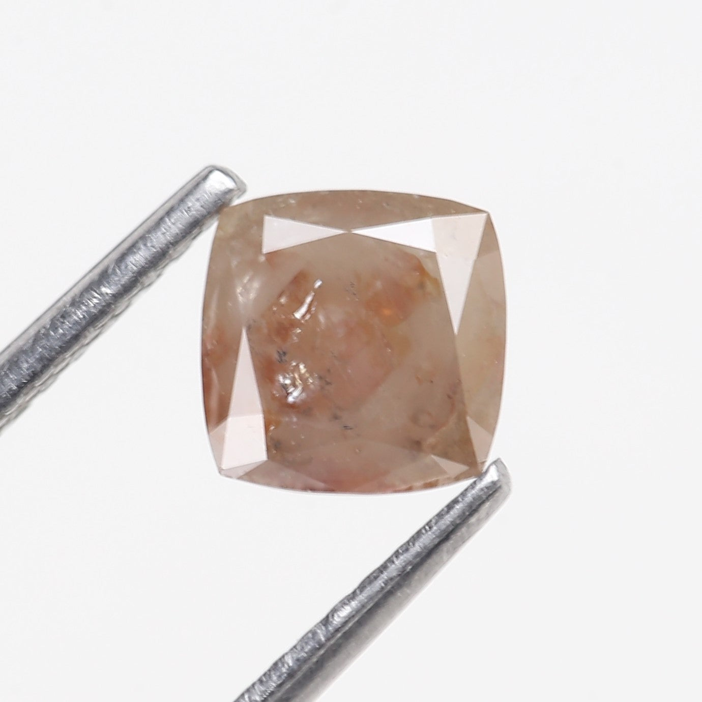Square-cut diamond with a metal rod for scale on a white background