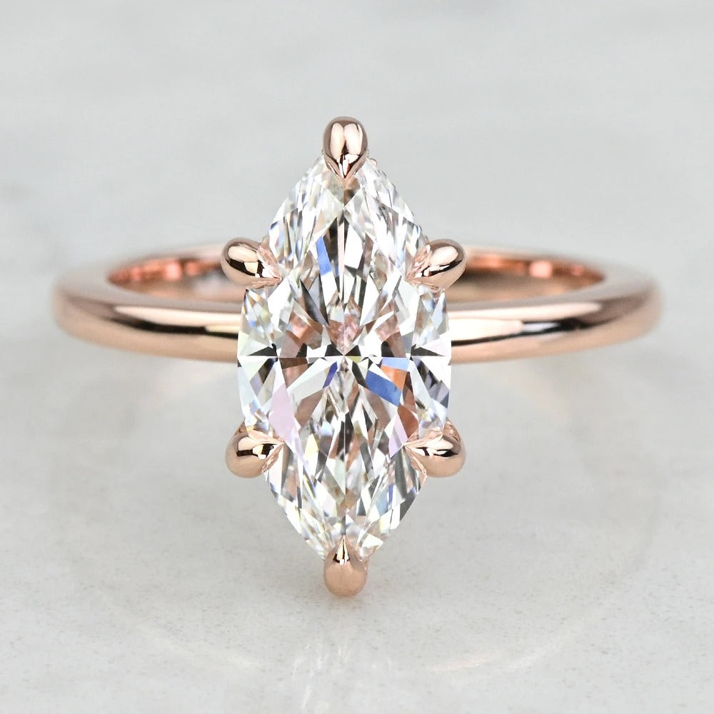 Rose gold ring with a marquise-shaped diamond on a light gray background
