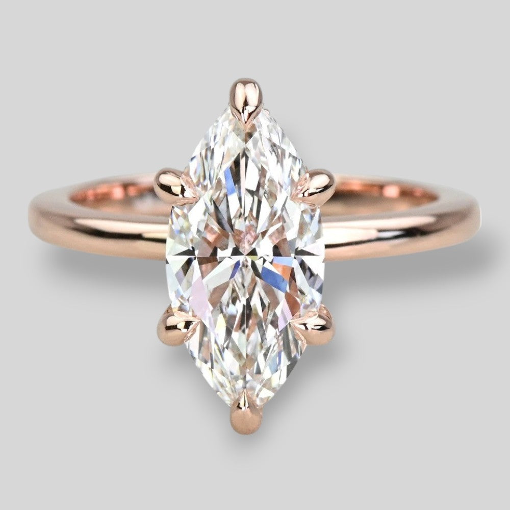 Rose gold ring with a pear shaped diamond on a light gray background