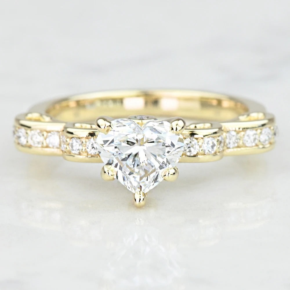 Gold ring with a heart-shaped diamond on a light background