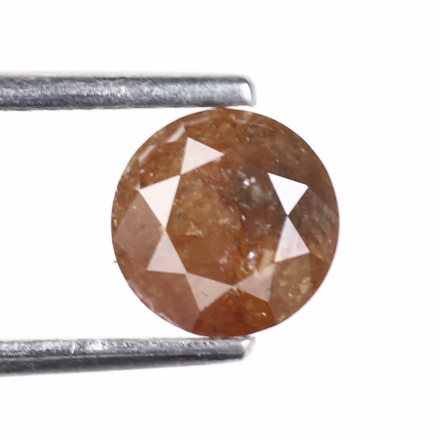 Brown diamond held by tweezers on a white background