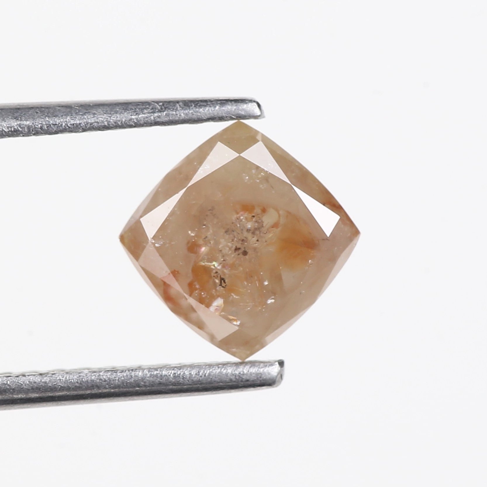 Brown diamond held between tweezers on a white background