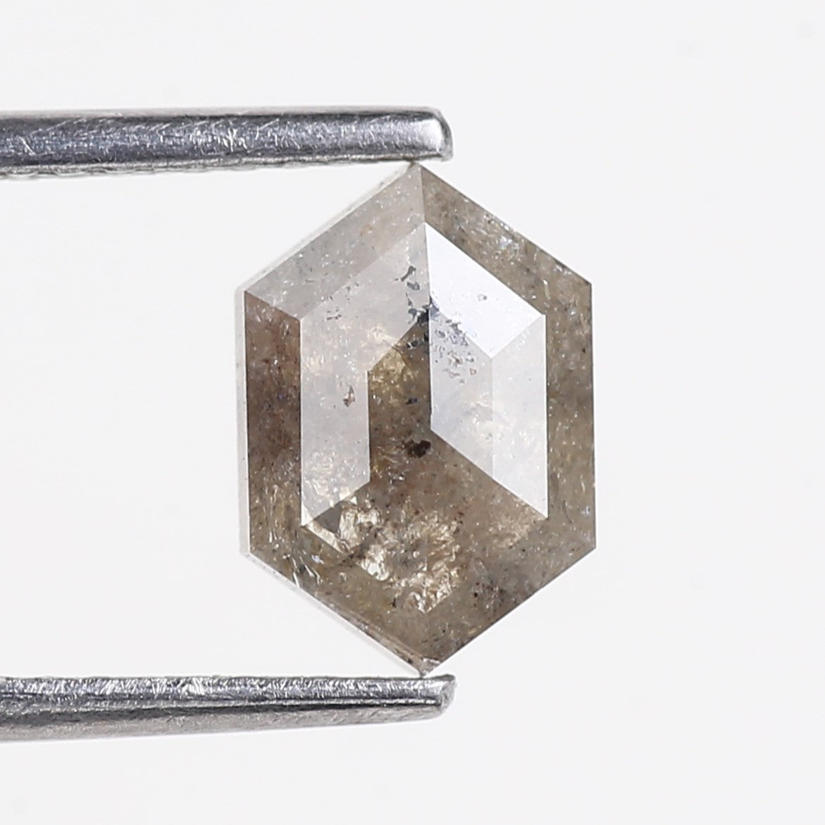 Hexagonal crystal held by tweezers on a white background