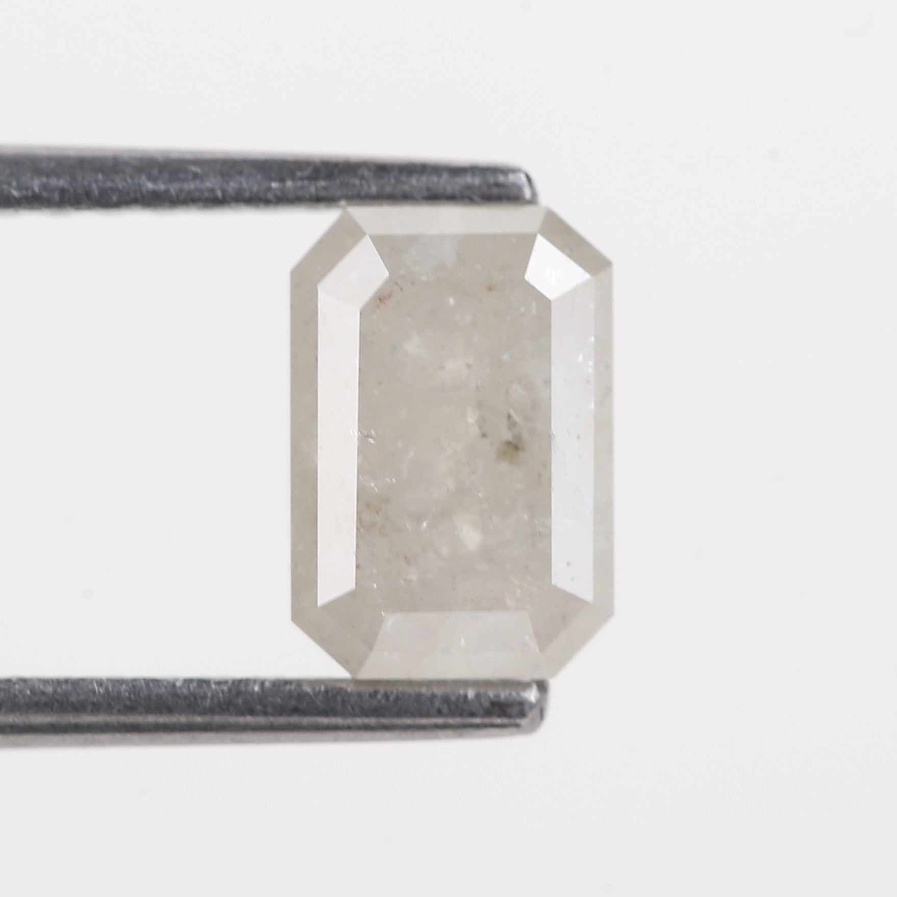 Rectangular diamond held between two metal prongs on a light gray background