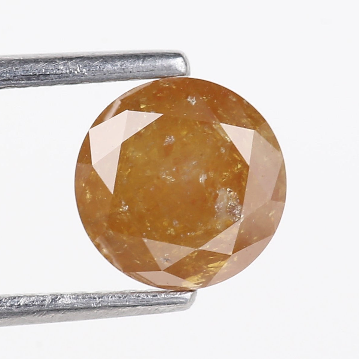 Round-cut yellow gemstone held between tweezers on a white background