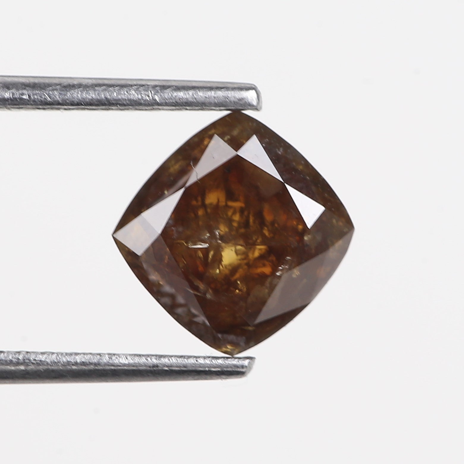 Brown diamond held between two silver prongs on a white background