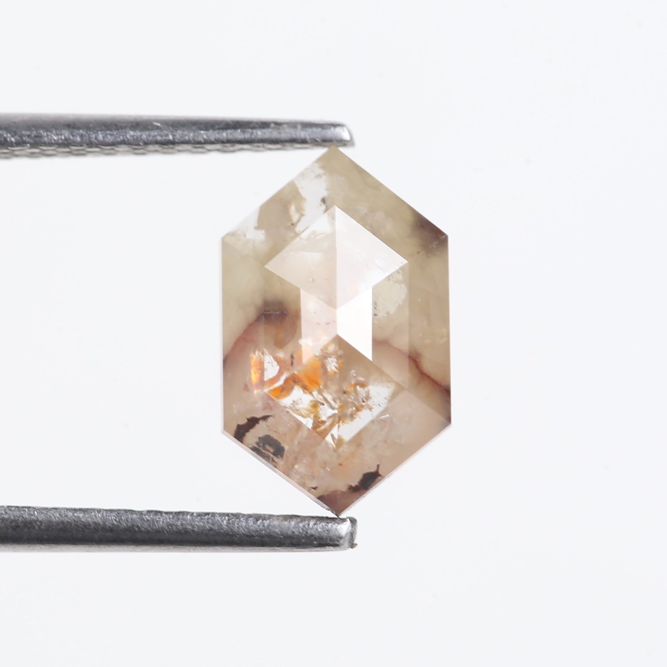 Hexagonal diamond held between tweezers on a white background