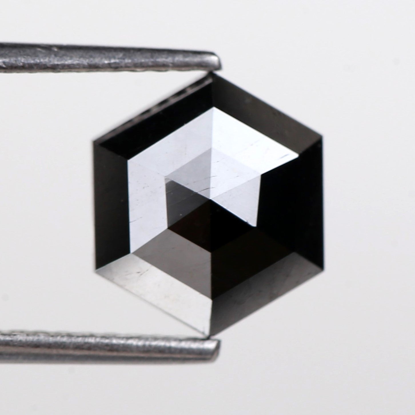 Black diamond held between two metal prongs on a white background