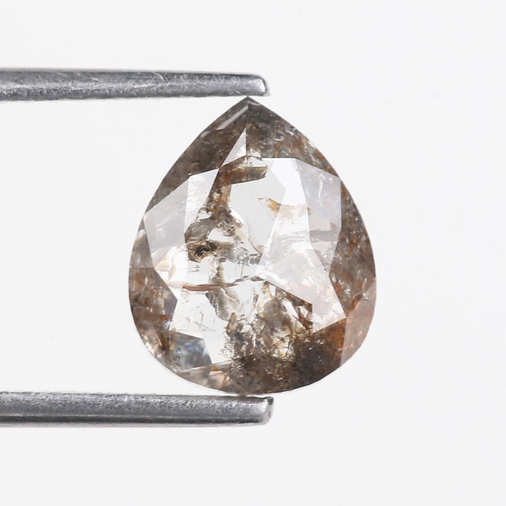Teardrop-shaped diamond held between two metal prongs on a white background