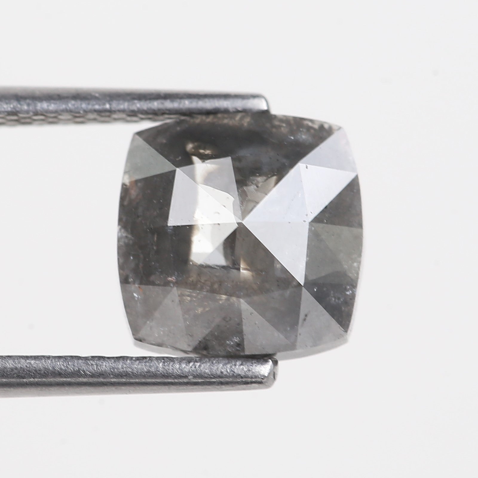 Gray diamond held by tweezers on a light gray background