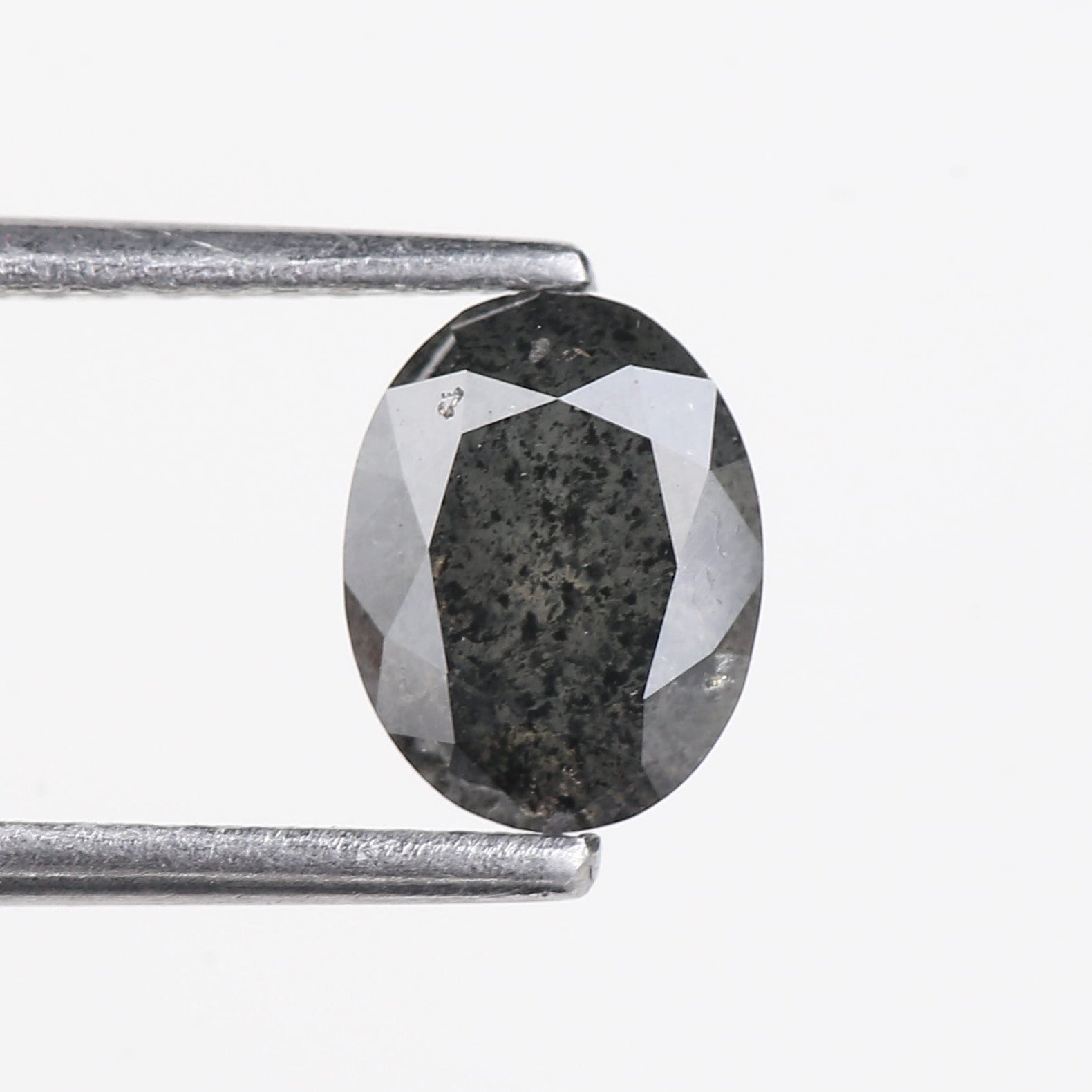 Faceted gemstone held between tweezers on a white background