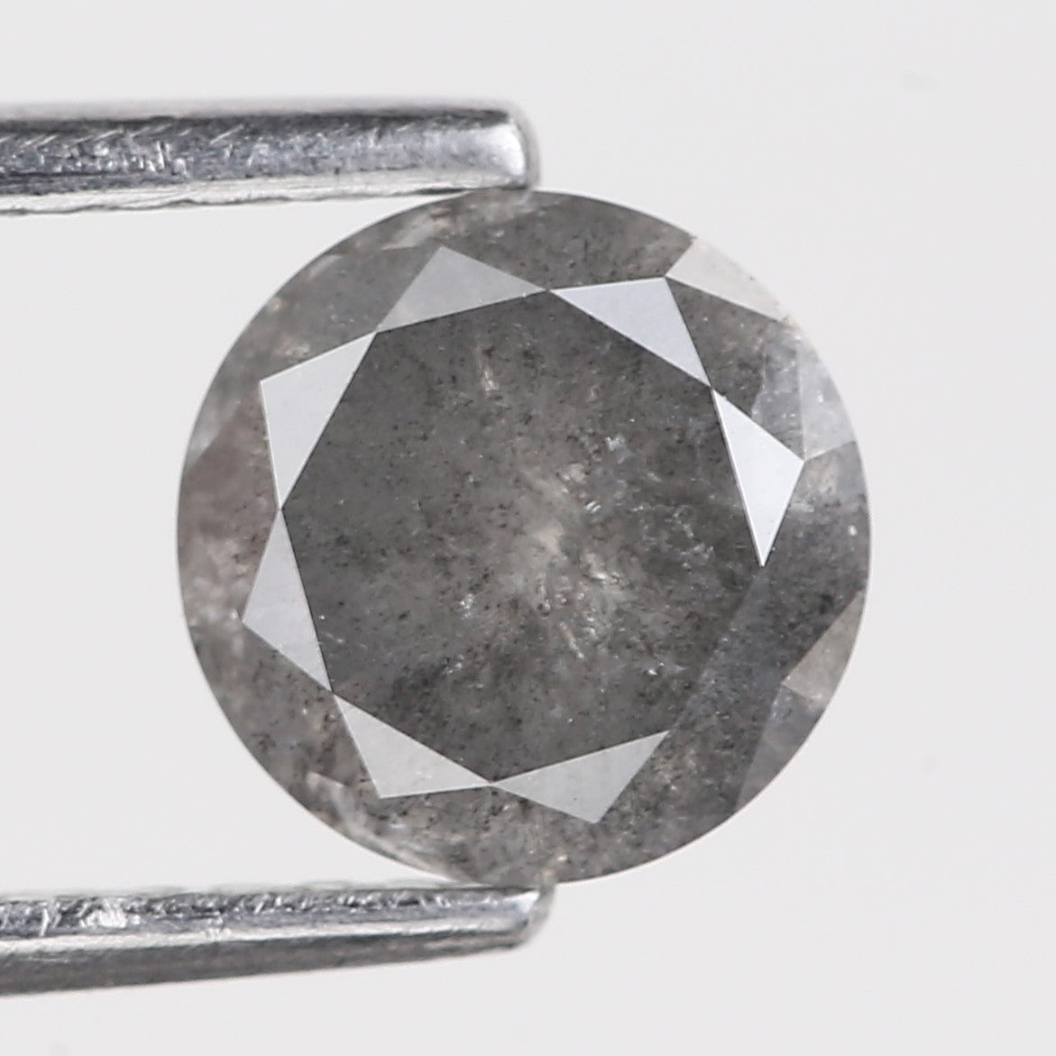 stormy Gray diamond held between two metal prongs on a white background