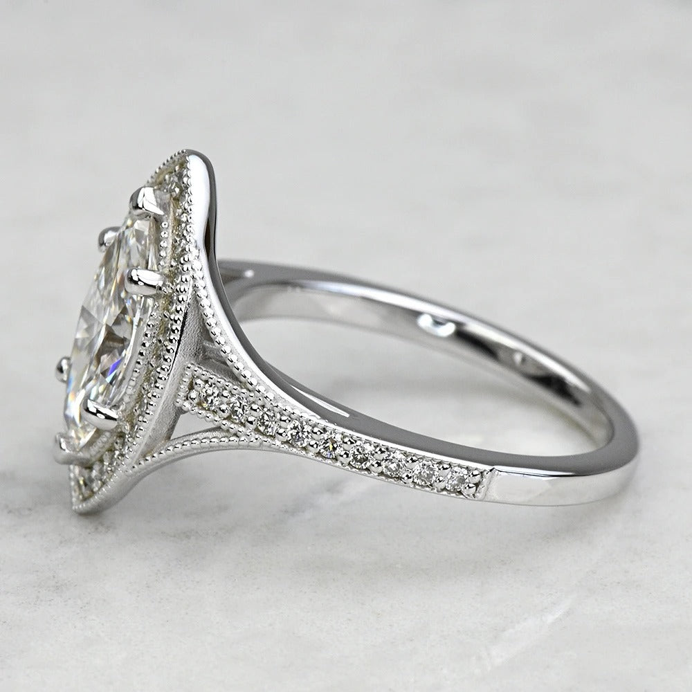 Silver ring with a large diamond and smaller diamonds on the band against a light gray background