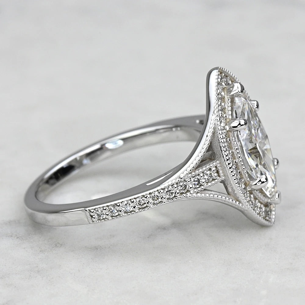 Silver ring with a large central gemstone and smaller stones on a light gray background