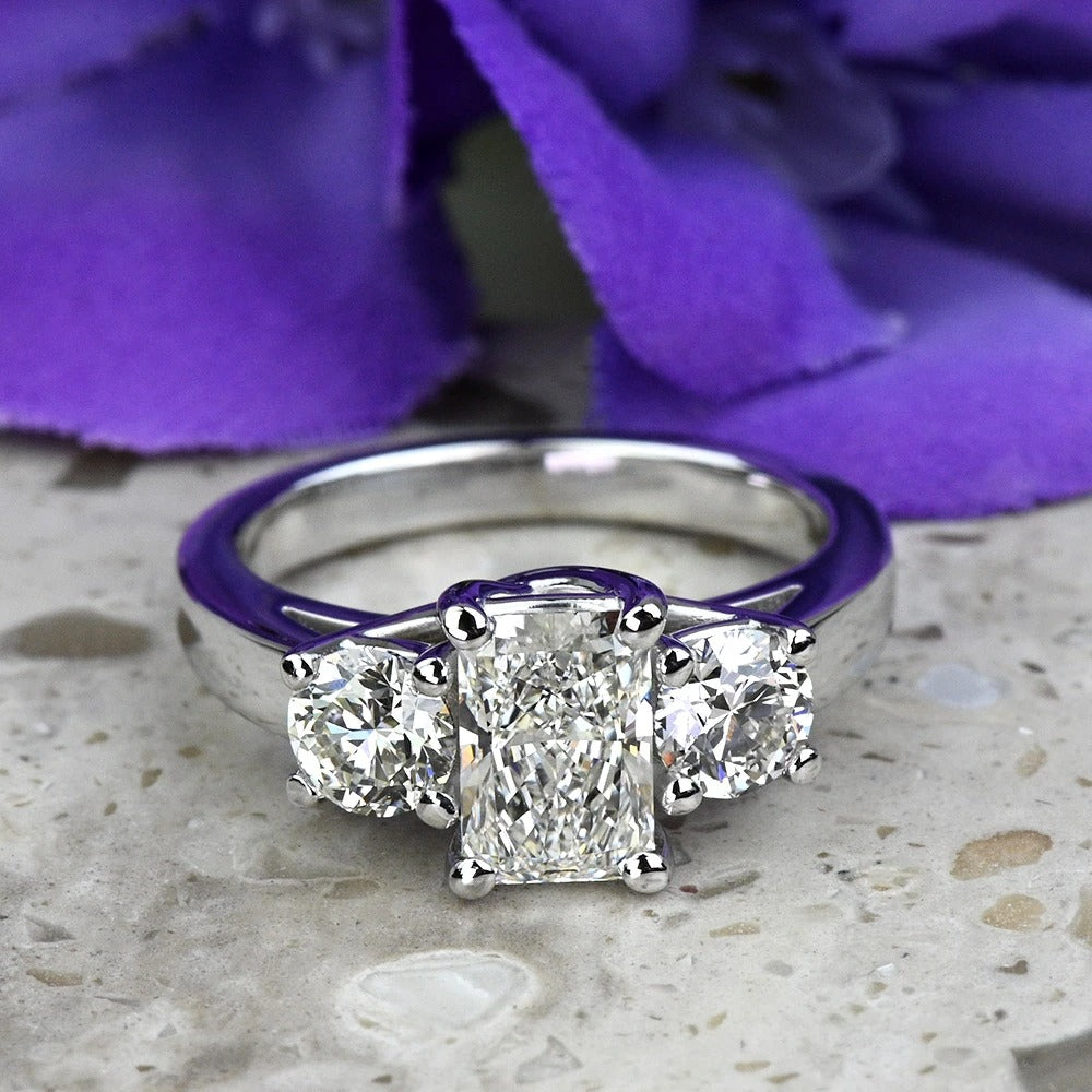 Diamond ring with purple accents on a textured surface with purple flowers in the background