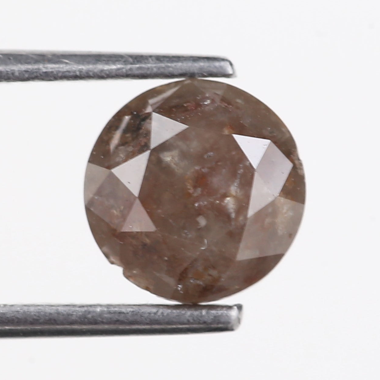 Brown diamond held between two metal sticks on a white background