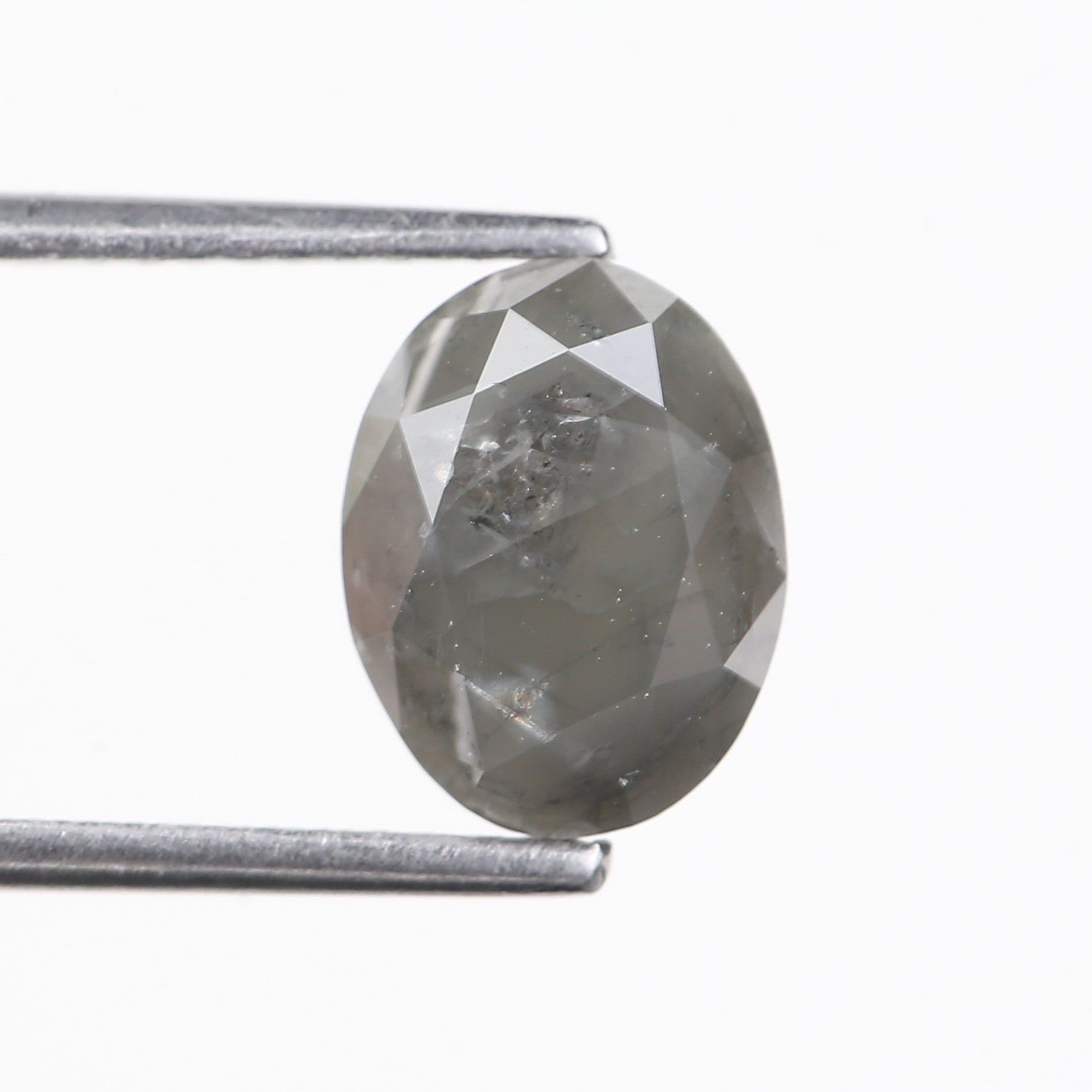 Faceted gemstone held by tweezers on a white background