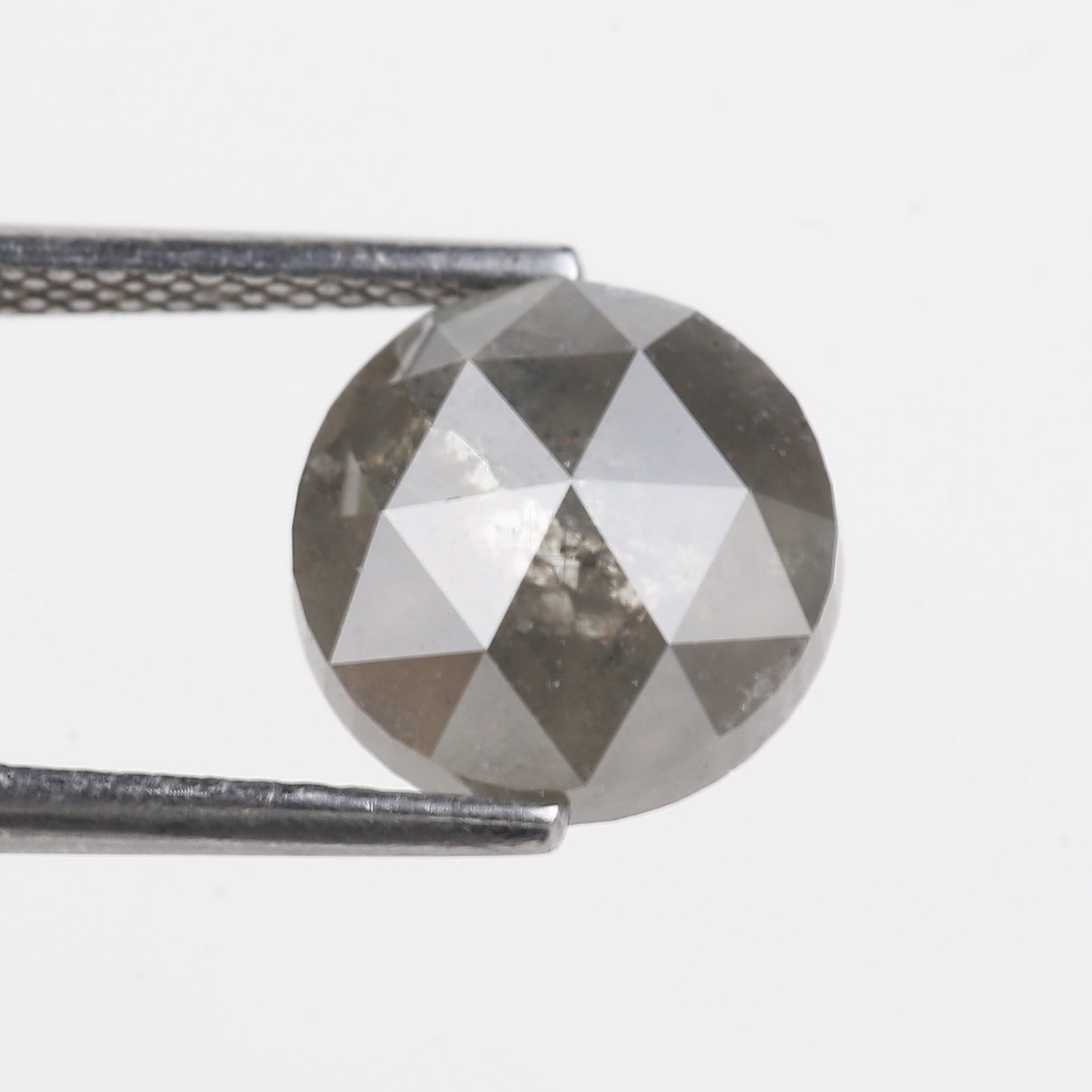 Faceted Diamond held between tweezers on a light gray background