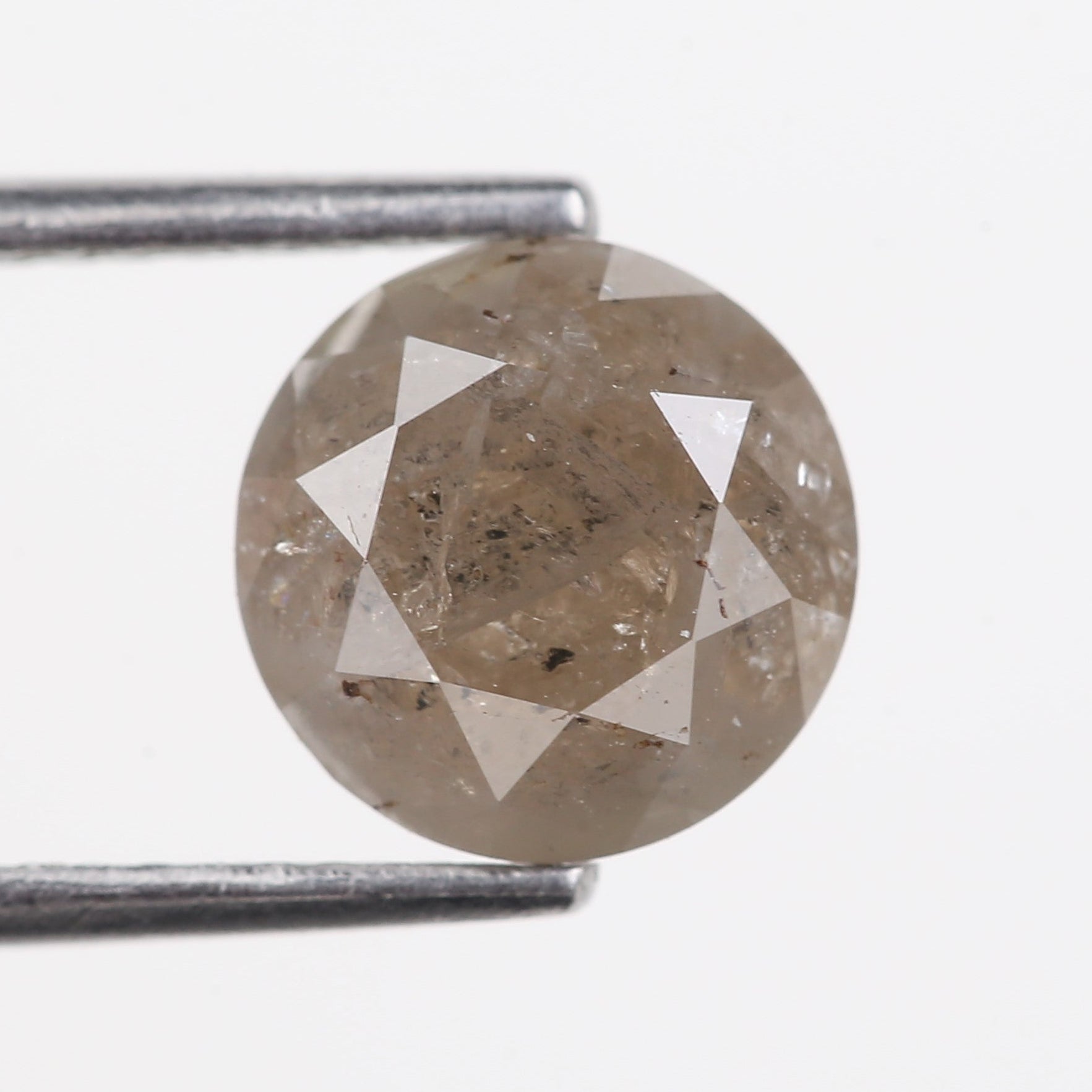 Round diamond held between tweezers on a white background