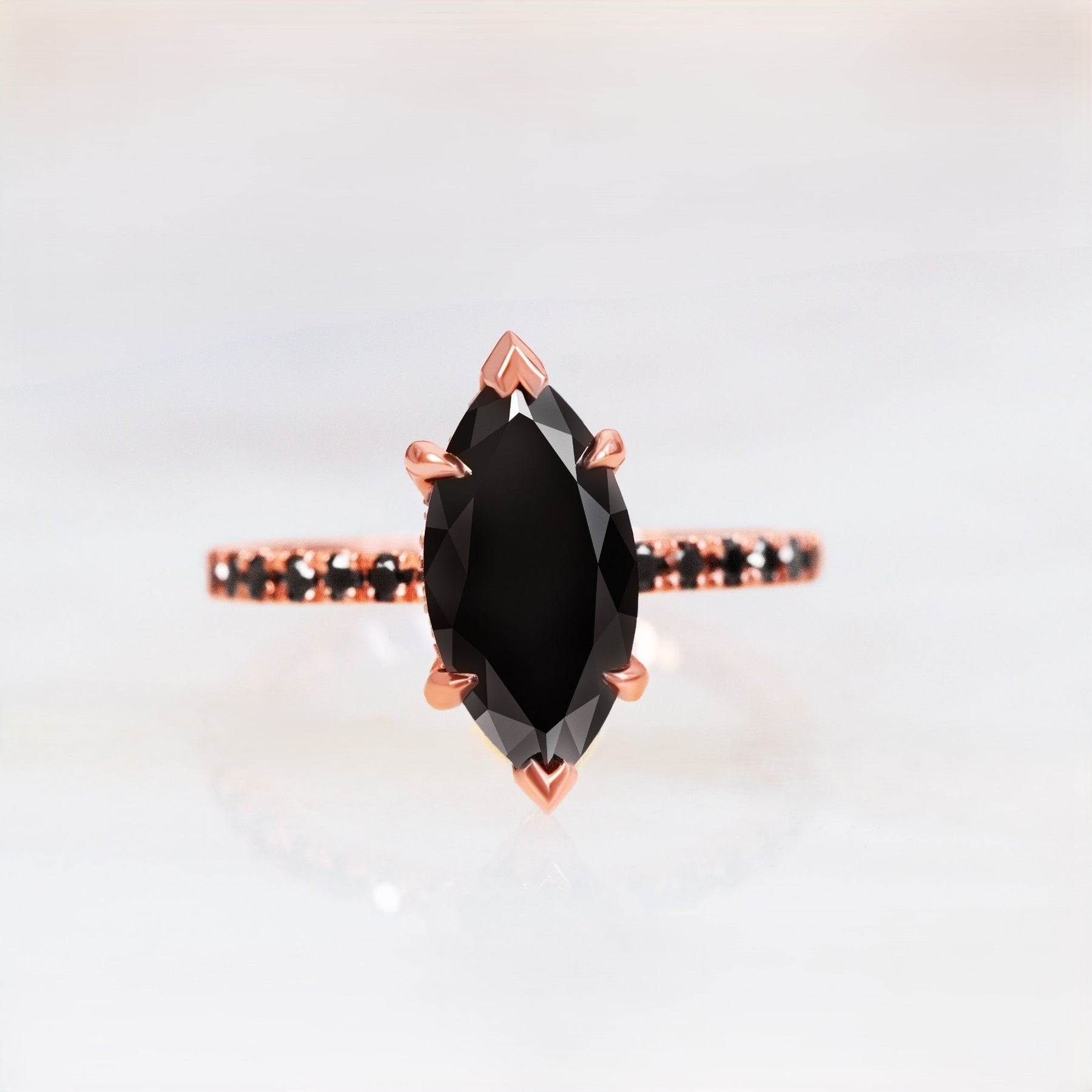 A marquise black diamond engagement ring with pave set round black diamonds on a 14k rose gold band.