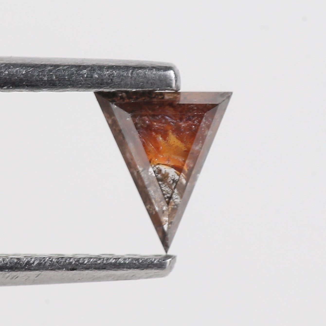 Diamond held between two tweezers on a light gray background