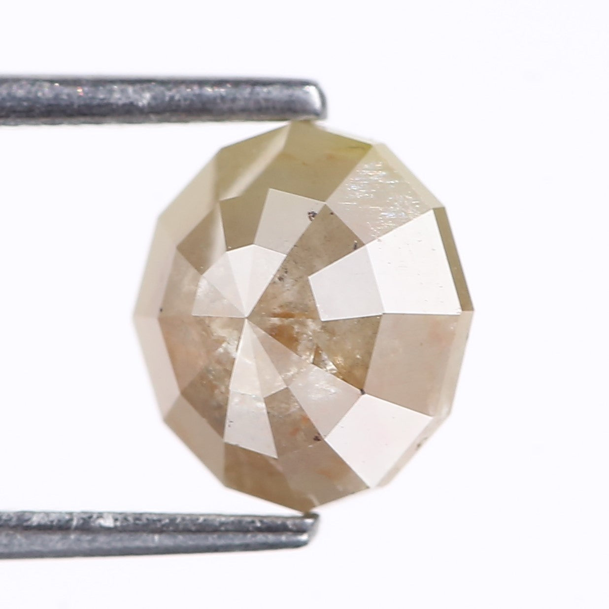 Faceted diamond held between two metal prongs on a white background