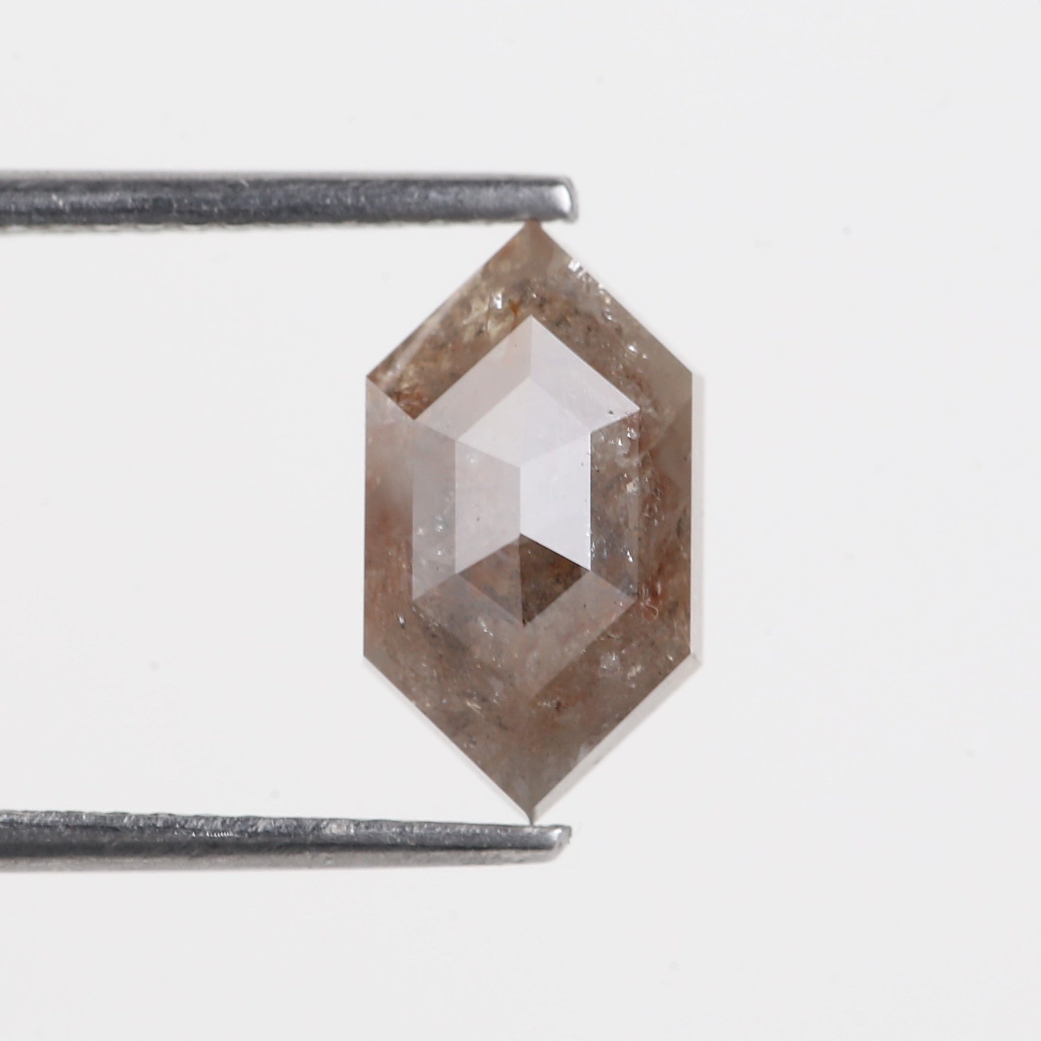 Hexagonal diamond held by tweezers on a light gray background