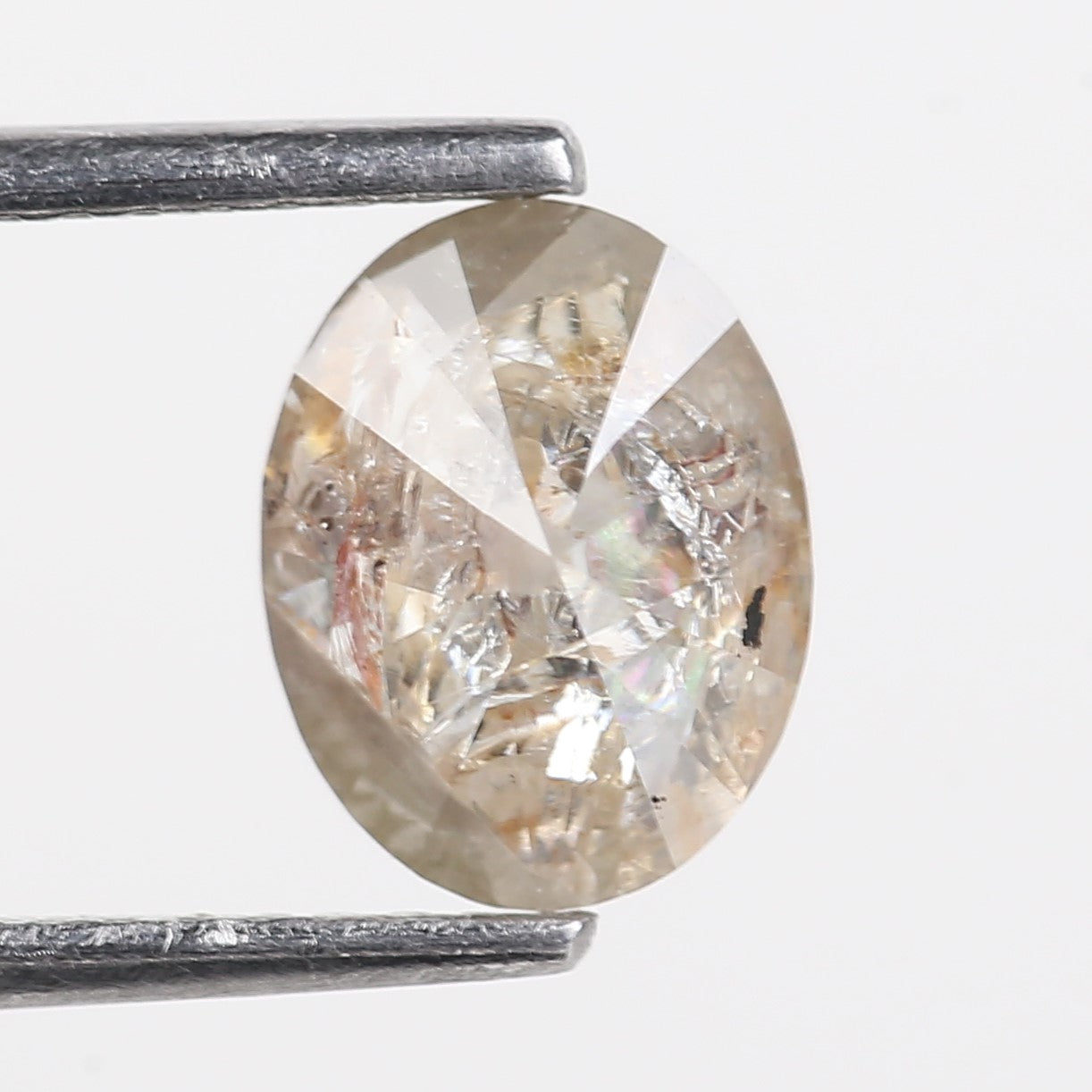 Diamond held between two metal prongs against a white background