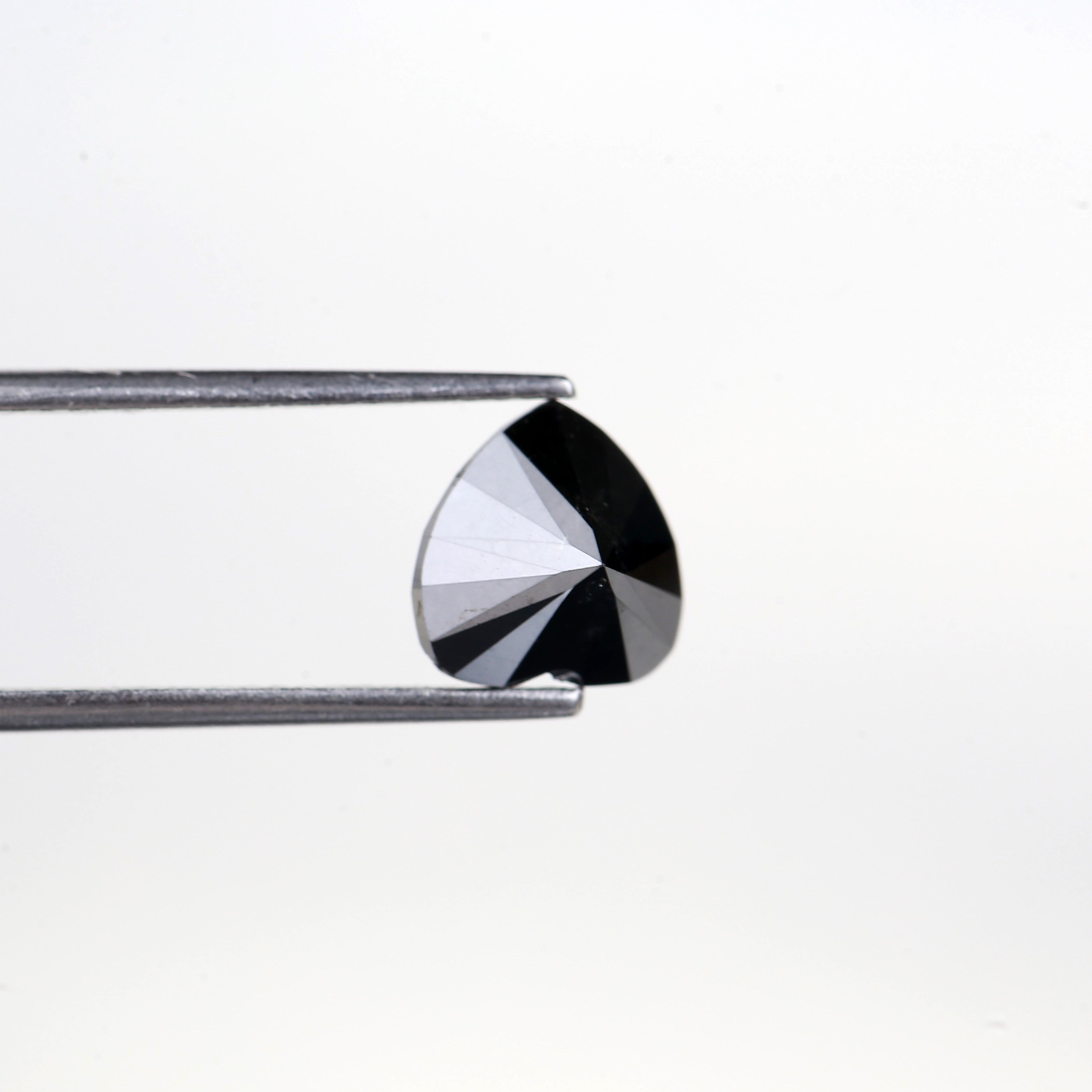 Faceted gemstone held by tweezers on a white background