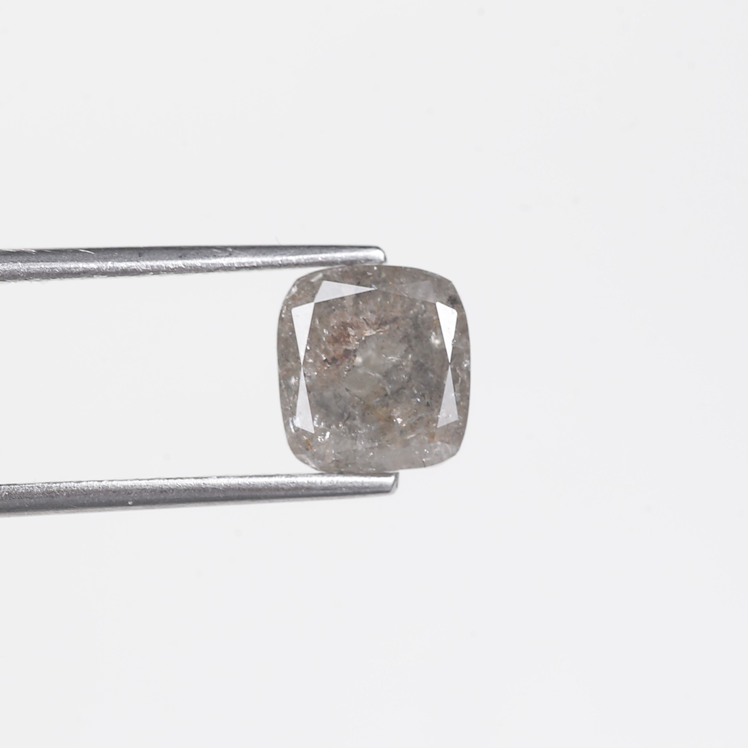 Diamond held by tweezers on a light gray background