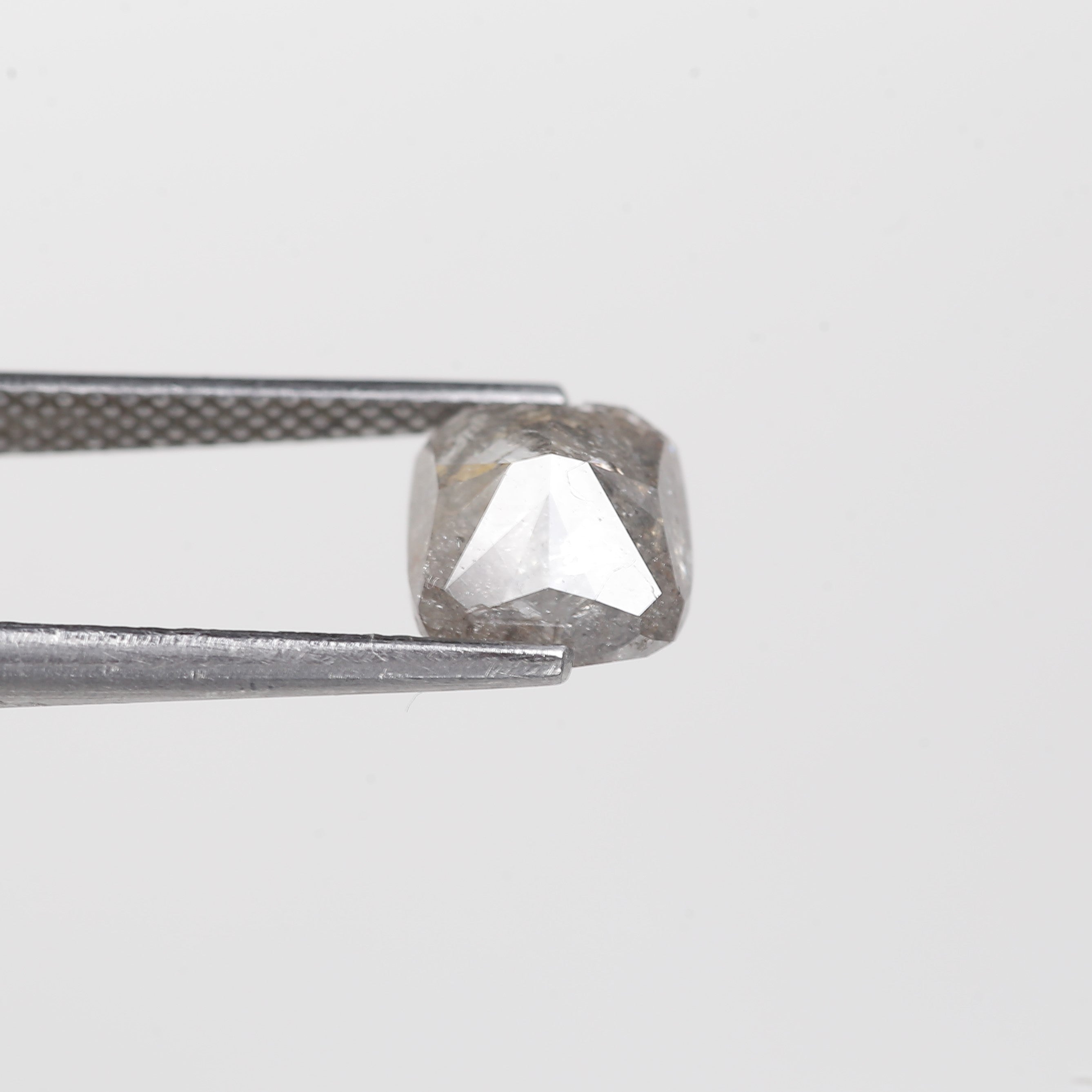 Diamond held between tweezers on a light gray background