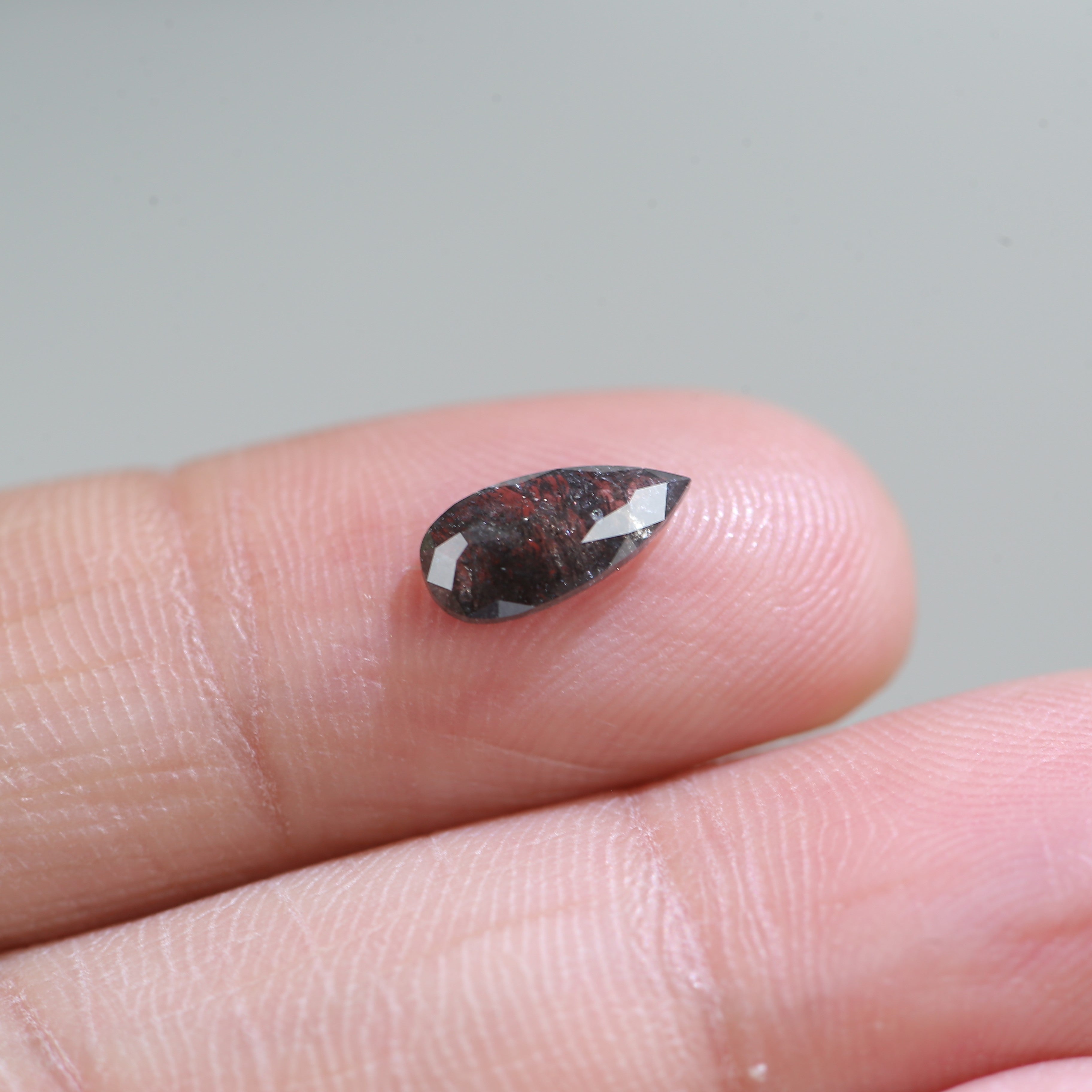 Faceted gemstone held between fingers against a neutral background