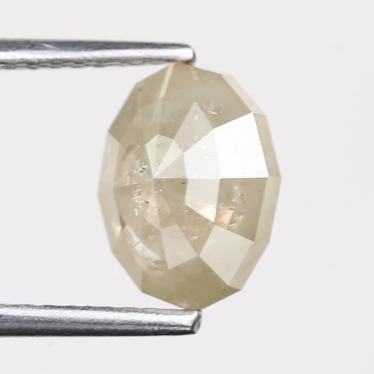 Faceted diamond held between tweezers on a white background