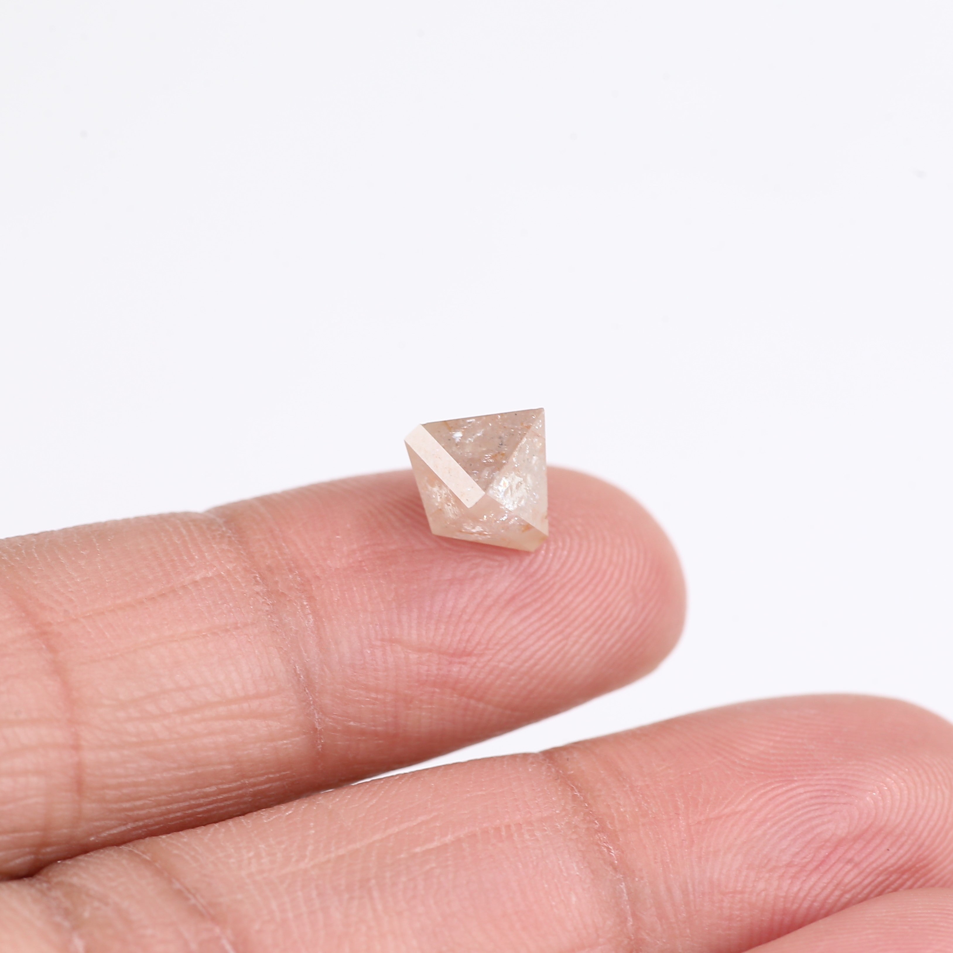 Small diamond held between fingers on a white background