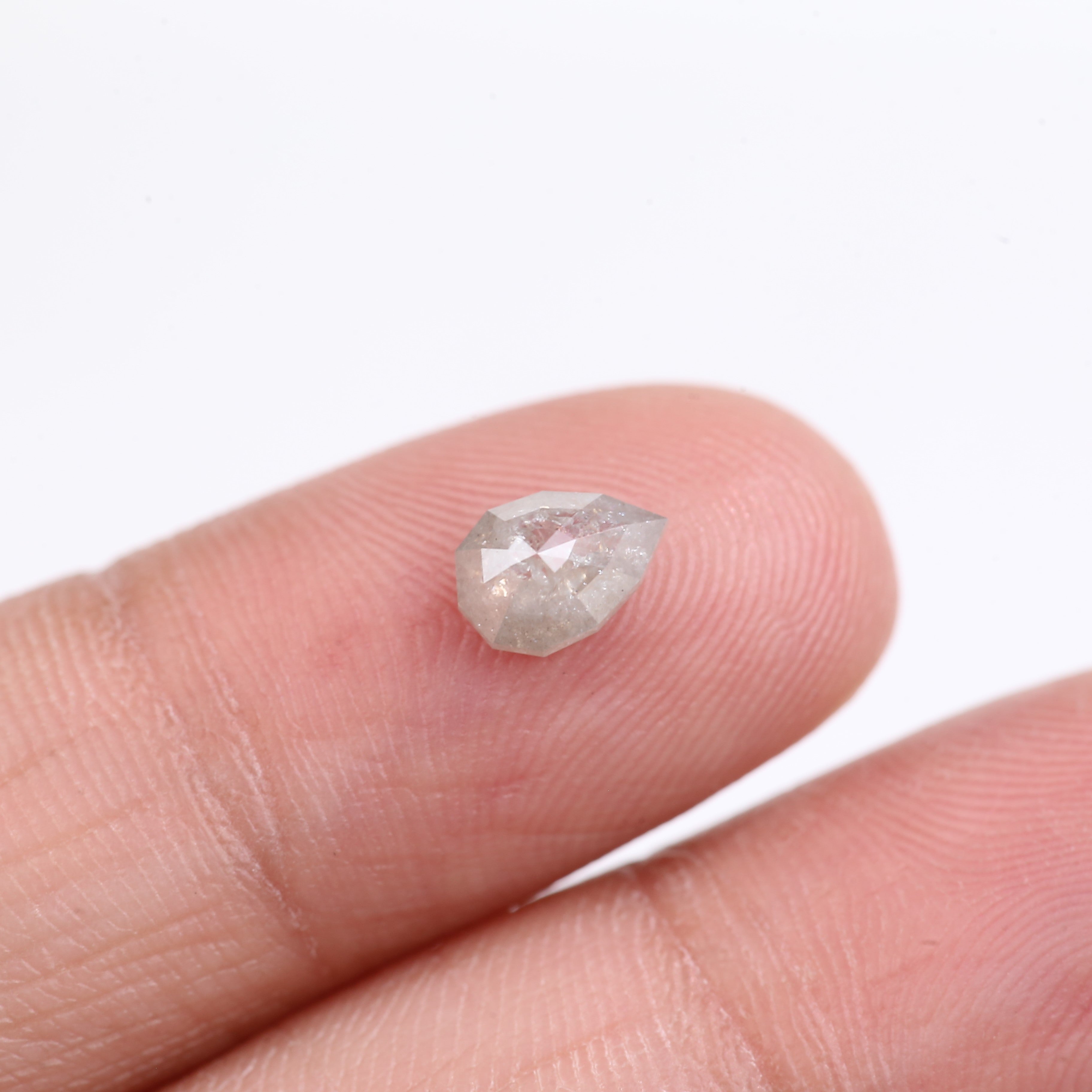 Raw diamond held between fingers against a white background