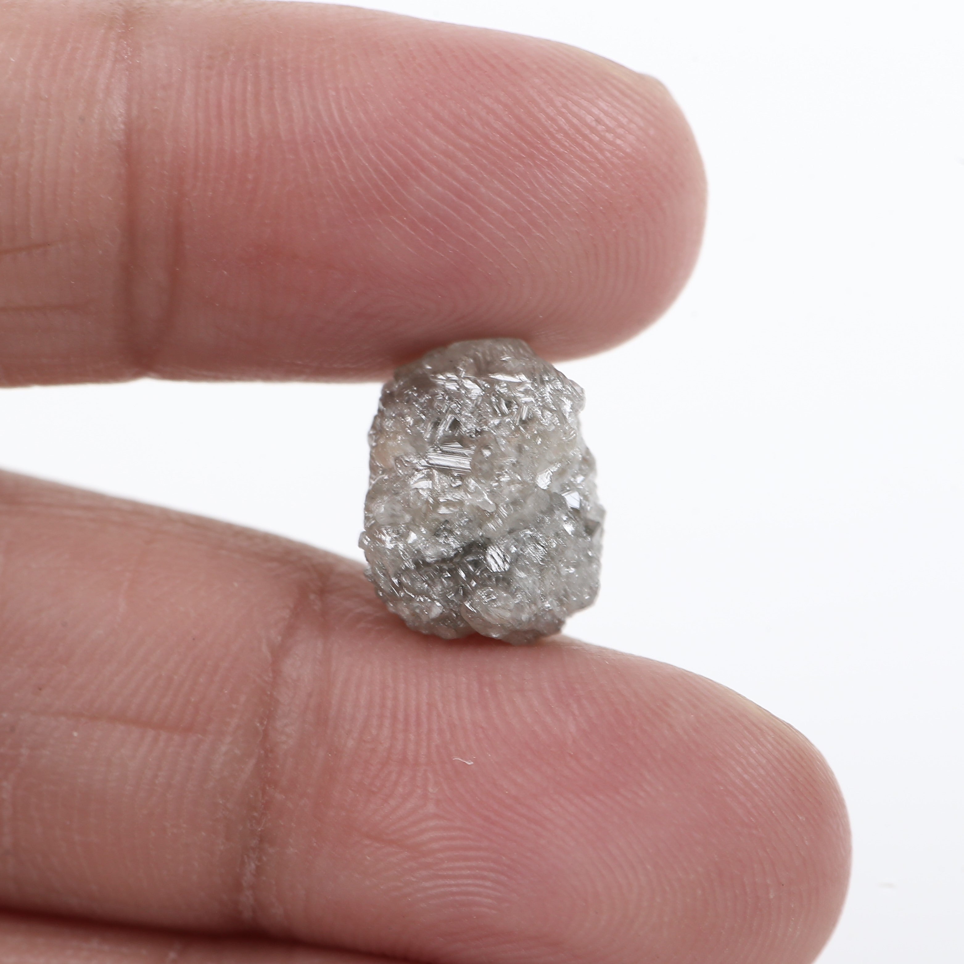 Raw diamond held between fingers against a white background
