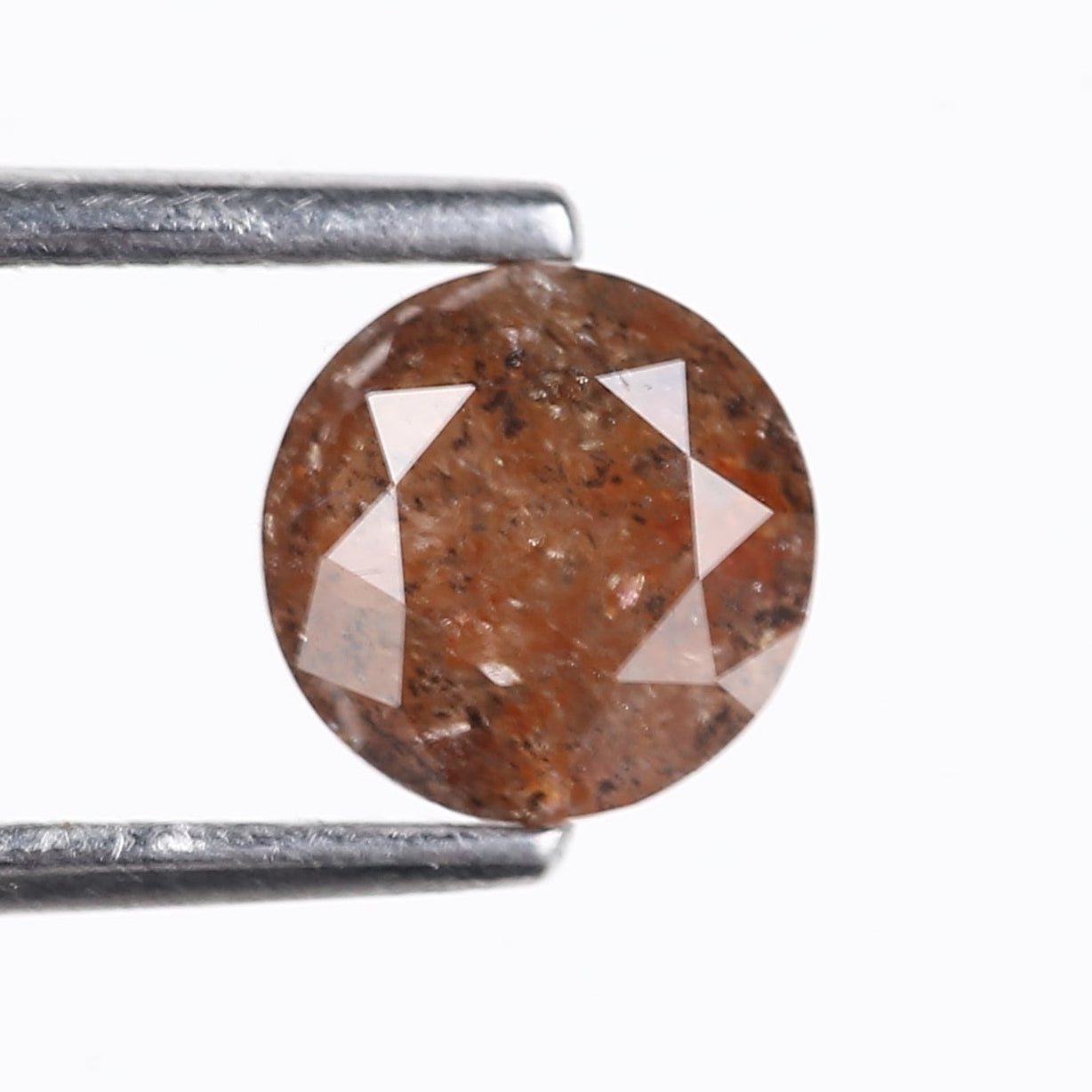 Brown diamond held between tweezers on a white background