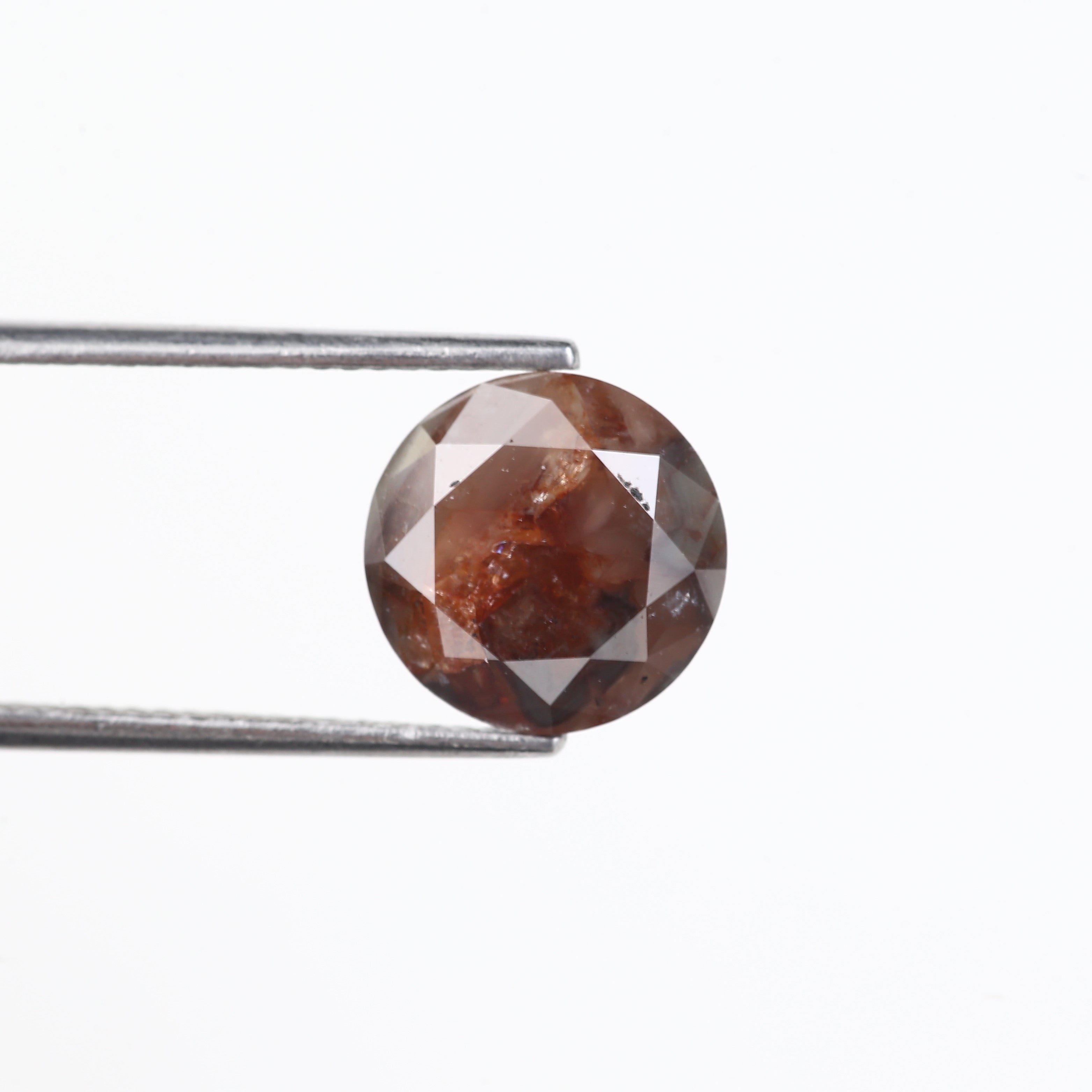 Brown diamond held by tweezers on a white background