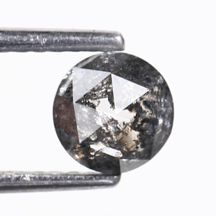 Round diamond held between tweezers on a white background