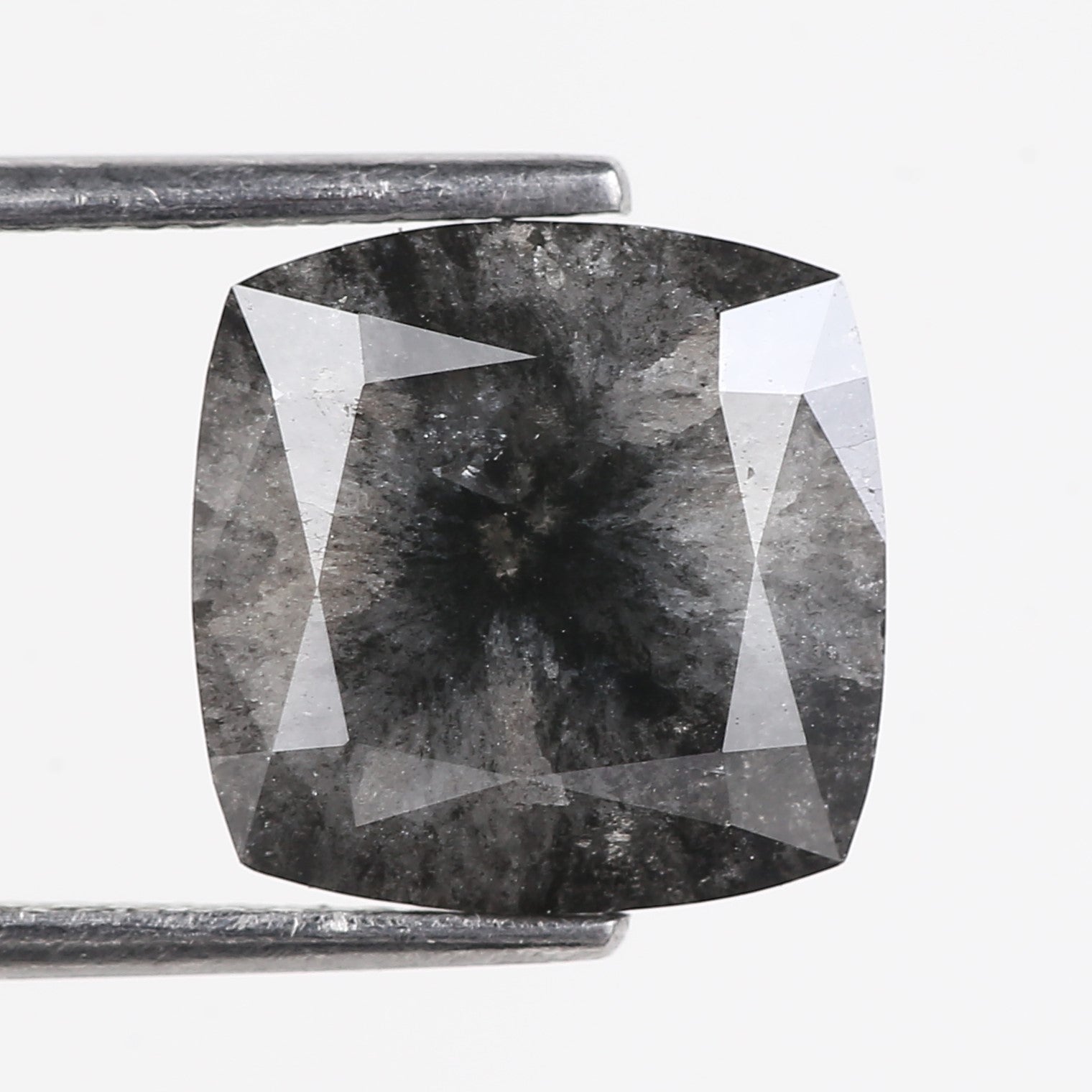 Black diamond held by tweezers on a white background