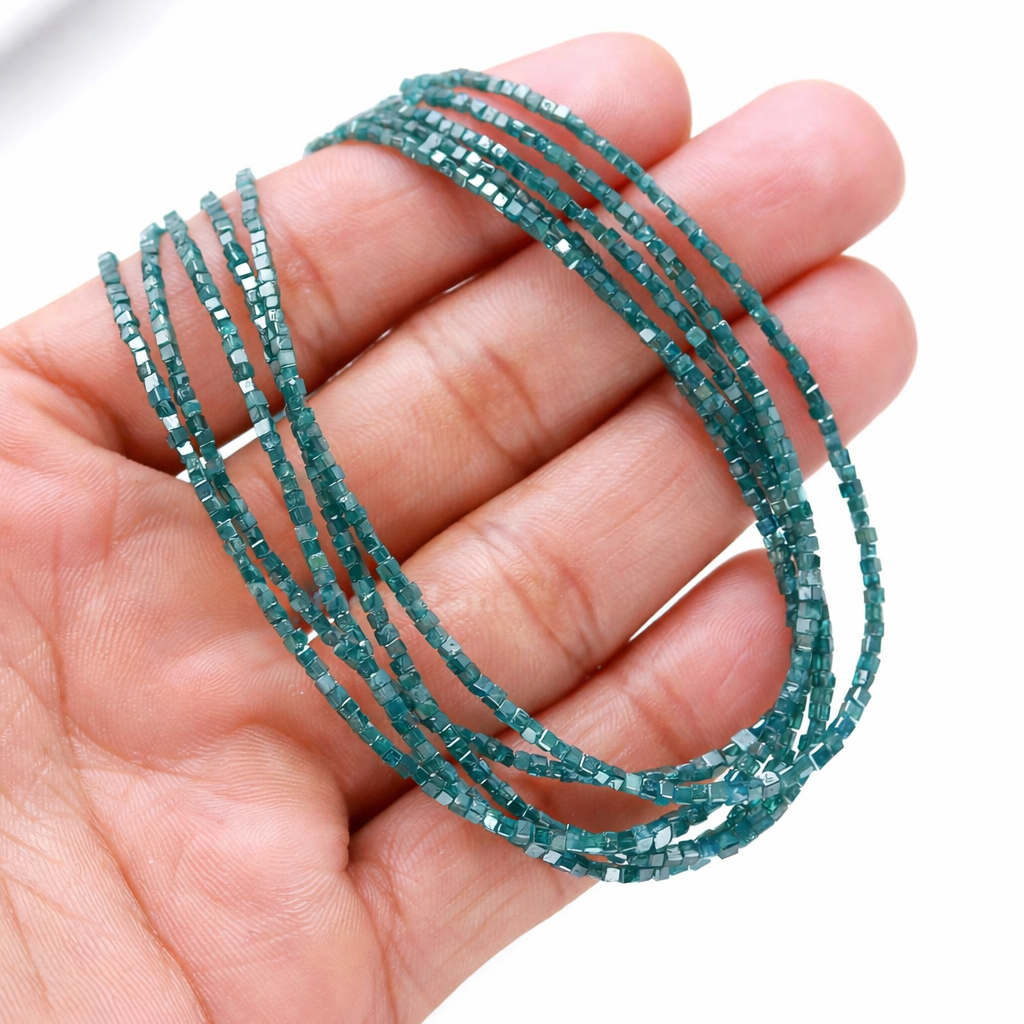 Teal beaded strands held in a hand against a white background